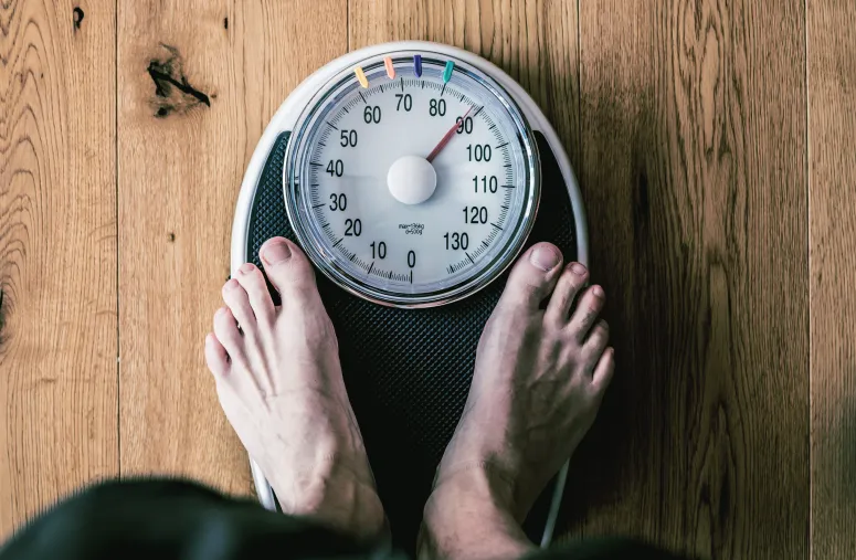 Scale showing weight measurements with comparison between fat loss vs weight loss concepts for body transformation