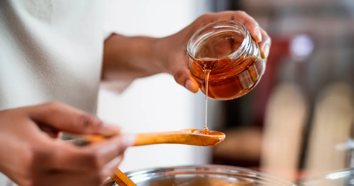 Natural honey in jar with honeycomb background - ancient therapeutic sweetener for intermittent fasting