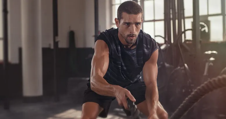 Athletic man doing battle ropes workout while intermittent fasting to retain muscle and lose body fat