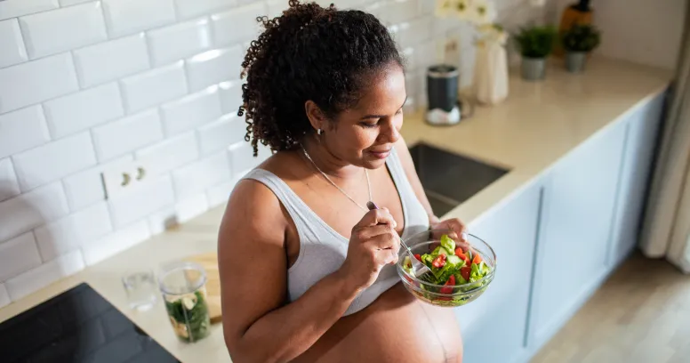 Pregnant woman eating healthy salad prioritizing steady nourishment over fasting