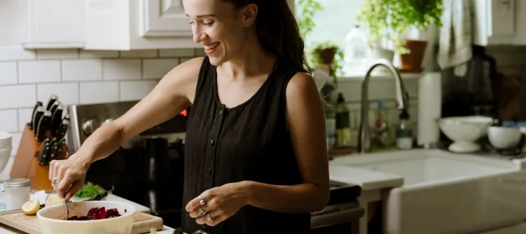 Fit woman cooking healthy food at home with olive oil for sustainable 16:8 intermittent fasting meal plan